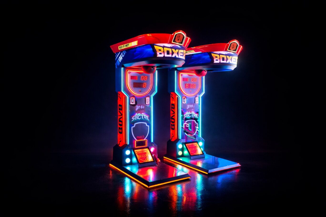 Dos máquinas recreativas de boxeo brillantes en un entorno oscuro con luces de neón.